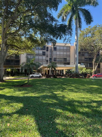 Front view of a multi-story building with a shaded entrance and surrounding palm trees.