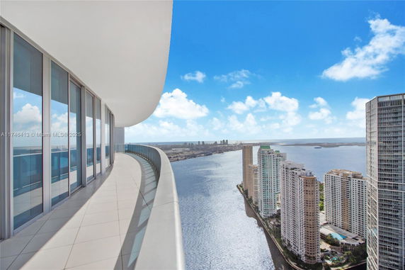Panoramic view of skyscrapers and water from a curved balcony.