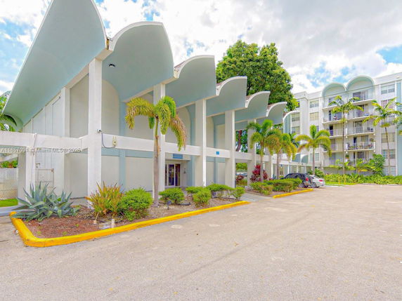 Front view of a building with distinctive arch-shaped roof and multiple floors.