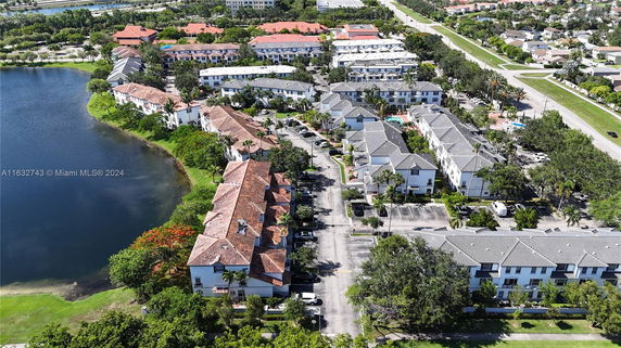 Aerial view of residential buildings near a lake with surrounding greenery.