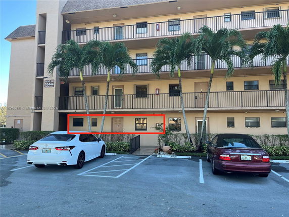 Front view of a multi-story residential building with balconies and parking area.