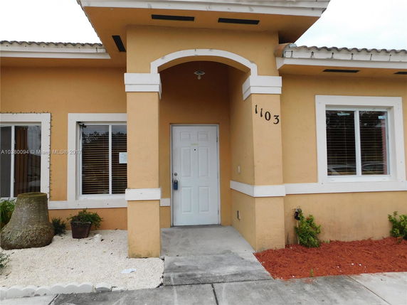 Front view of a house with an arched entryway and white-framed windows.