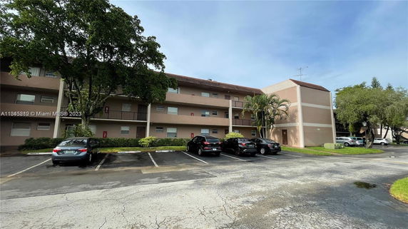 Front view of a three-story apartment building with parking spaces.