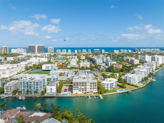 High-angle view of a coastal city with several mid-rise buildings and a body of water in the foreground.