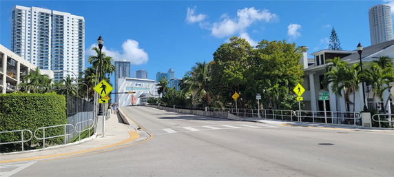 Street view with tall buildings and palm trees in an urban area.