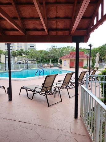 Outdoor swimming pool area with lounge chairs and a pergola.