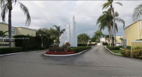 Front view of a residential gated community entrance with palm trees.
