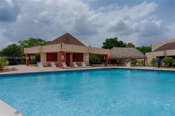 Outdoor swimming pool area with lounge chairs and a shaded pavilion.