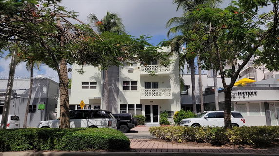 Front view of a three-story building with balconies and a decorative facade.