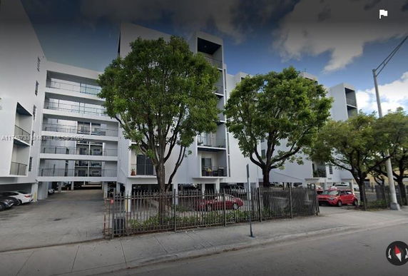 Front view of a multi-story residential building with balconies and parking area.