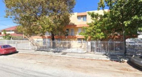 Front view of a multi-story residential building behind a metal fence.