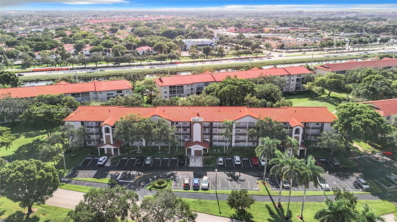 Aerial view of apartment buildings with red roofs surrounded by greenery.