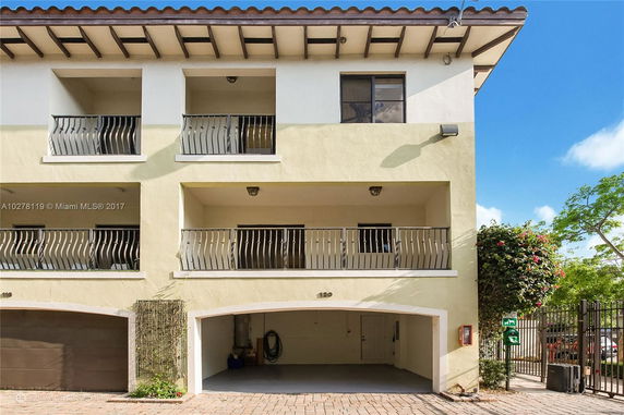 Front view of a multi-story building with balconies and an open garage.