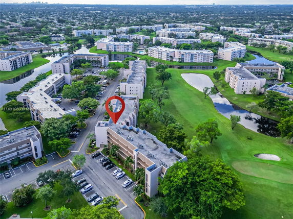 Panoramic aerial view of a residential apartment complex with surrounding green areas and water bodies.