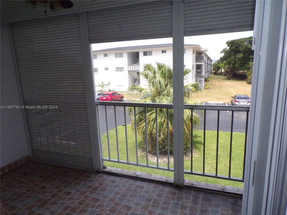View from a balcony showing a multi-story residential building and green surroundings.
