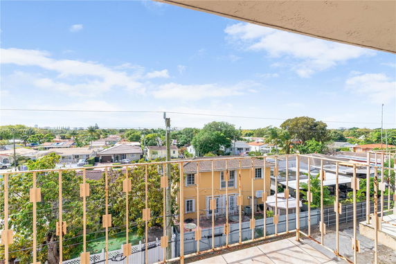 Panoramic view from a building overlooking residential area with houses and greenery.