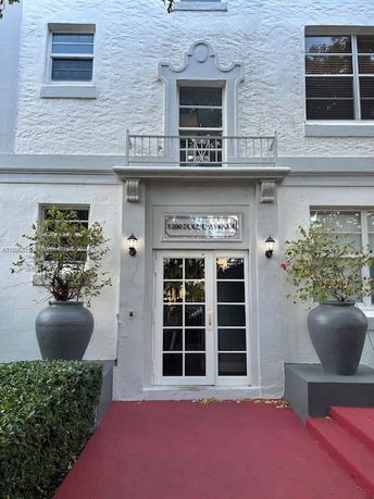 Front view of a building with a white facade and decorative elements above the door.