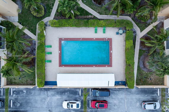 Aerial view of a rectangular swimming pool surrounded by greenery and lounge chairs.