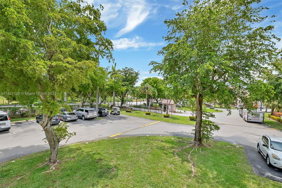 Outdoor parking area with multiple cars parked and surrounded by trees.