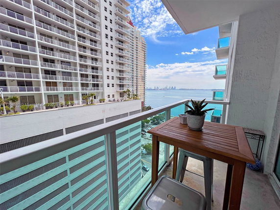 Balcony view from a high-rise building overlooking water and neighboring skyscrapers.