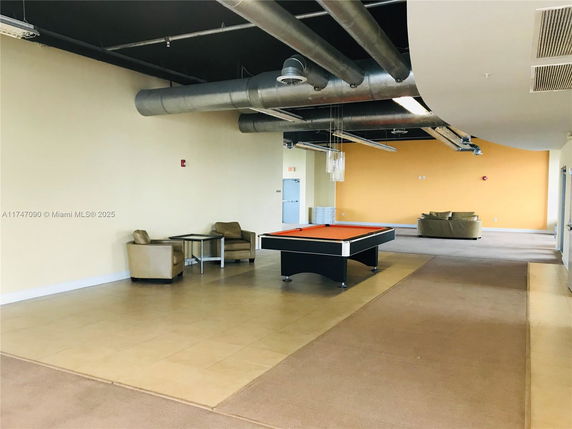 Room with pool table and seating area in a recreational space.