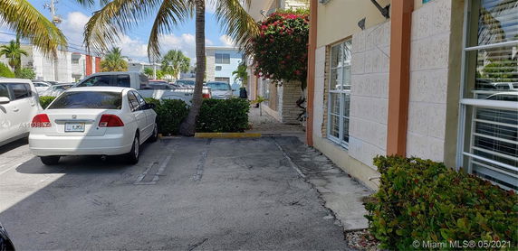Outdoor parking area with parked cars near a building facade.