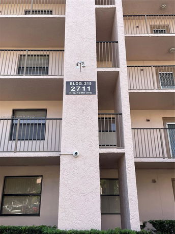 Front view of a multi-story building with balconies and signage displaying building number and address.
