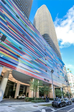 Front view of a modern high-rise building with a colorful striped facade.