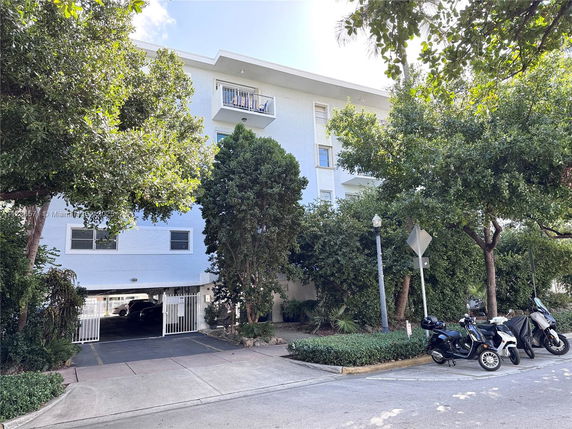 Front view of a multi-story building with balconies and a parking entrance.