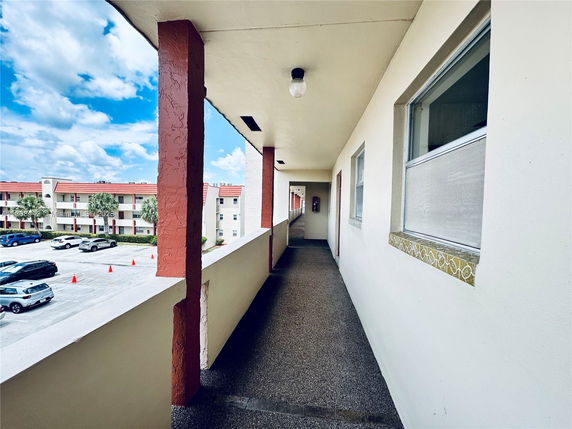 View from a building corridor overlooking a parking area and adjacent building.