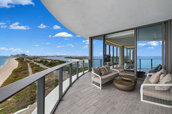Balcony with seating overlooking a beach and cityscape.
