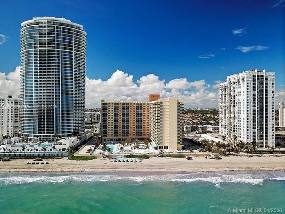 View of tall beachfront residential buildings with a pool and beach area.