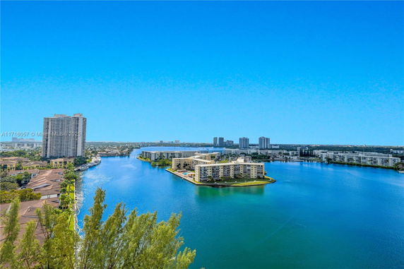 Aerial view of buildings adjacent to a body of water with a clear blue sky.