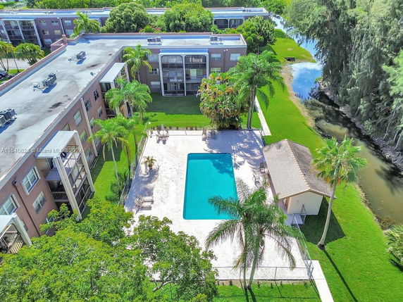 Aerial view of a multi-story residential building with a swimming pool in the courtyard.