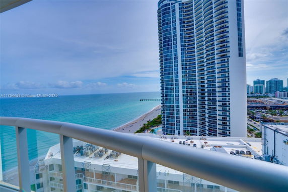 Panoramic view from a high-rise building overlooking the ocean and a nearby skyscraper.