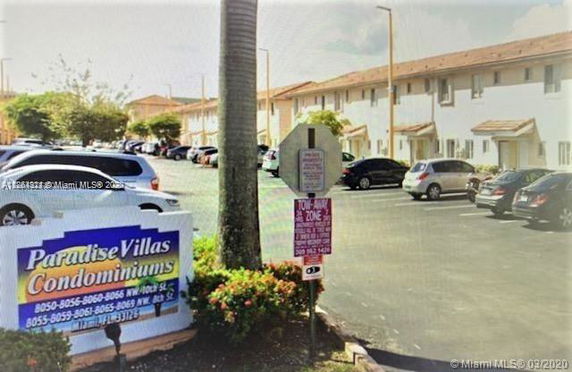 Outdoor parking area in front of condominiums with multiple parked cars.
