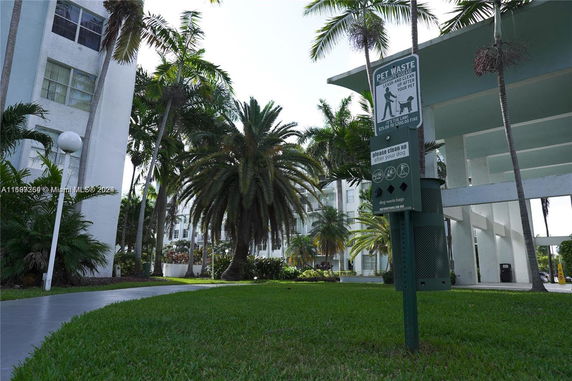 Exterior view of a residential building with palm trees and a pet waste station.