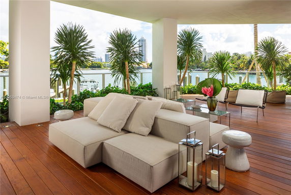 Outdoor seating area with a view of water and distant buildings.
