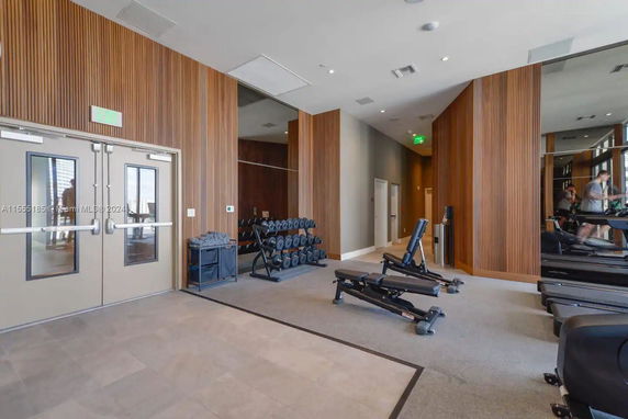 Interior of a modern gym with exercise equipment and wooden panel walls.