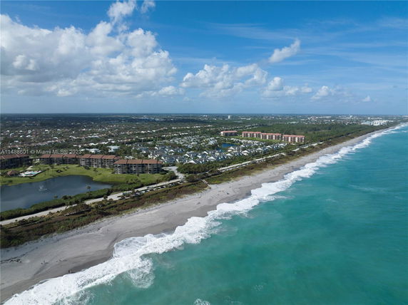 Aerial view of a coastal area with buildings, roads, and the ocean shoreline.