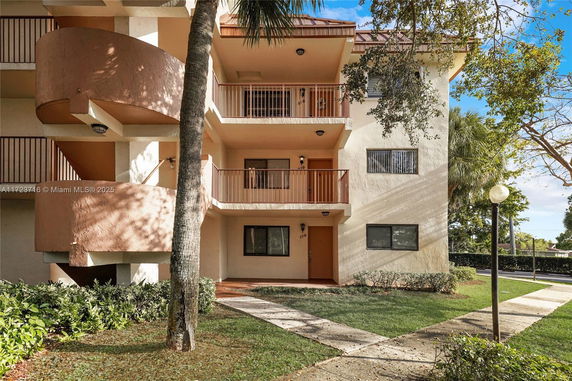 Front view of a multi-story residential building with balconies and a spiral staircase.