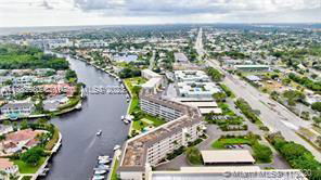 Aerial view of a riverside area with multiple buildings and a road running parallel to the water.