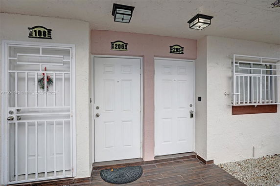 Front view of entrance doors to apartment units with a tiled walkway.