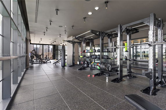 Interior view of a modern gym with various exercise equipment and floor-to-ceiling windows.
