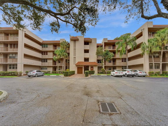 Front view of a multi-story residential building with balconies and an entrance.