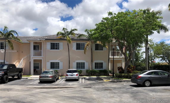 Front view of a two-story residential building with a parking area.