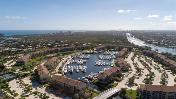 Aerial view of a residential marina complex with multiple buildings and a waterway filled with yachts.