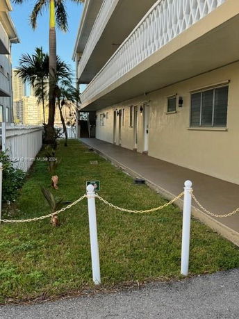 Side view of a multi-story building with a narrow walkway and grass area.