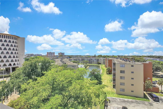 View of multiple residential buildings and trees with a clear blue sky.