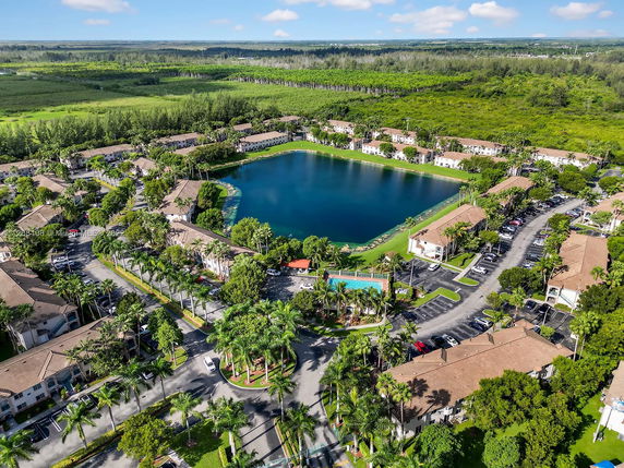 Aerial view of a residential community with a central lake and surrounding greenery.